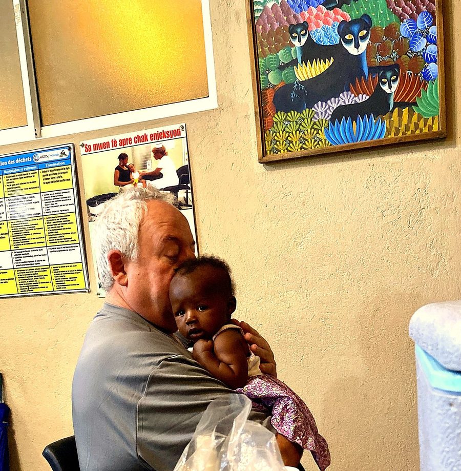 Randy Moore, RN, Cofounder of Sarepta Foundation, holding a baby at a clinic in Haiti